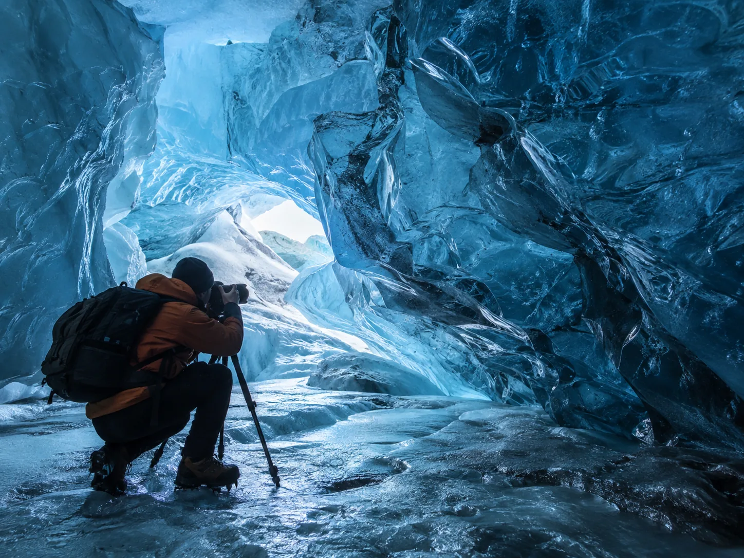 a photographer inside a blue ice cave.