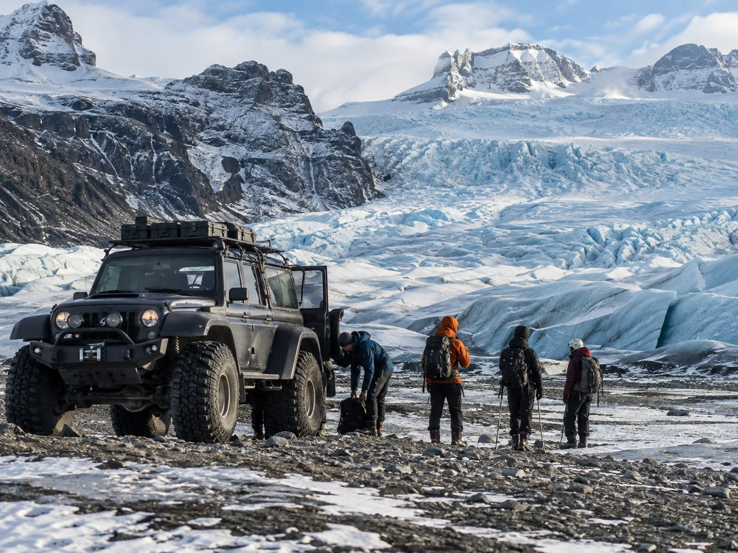 A modified four-wheel-drive vehicle beside a glacier.