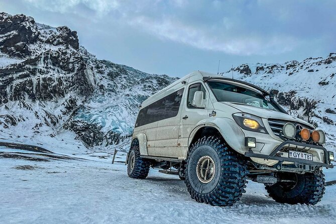 A Super Jeep is parked in a snowy area in Iceland near an ice cave.